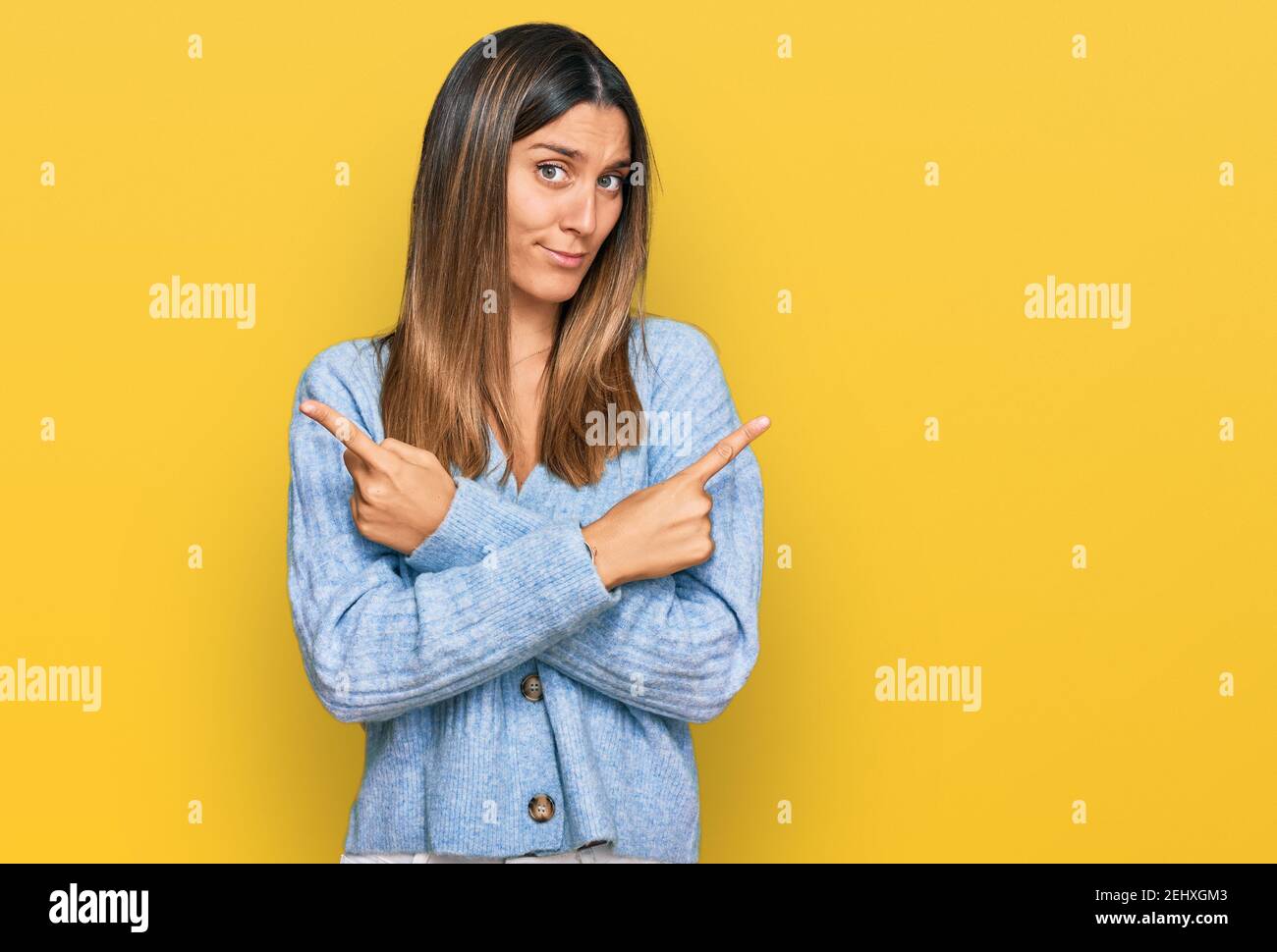 Junge Frau trägt legere Kleidung, die zu beiden Seiten mit den Fingern zeigt, unterschiedliche Richtung nicht einverstanden Stockfoto