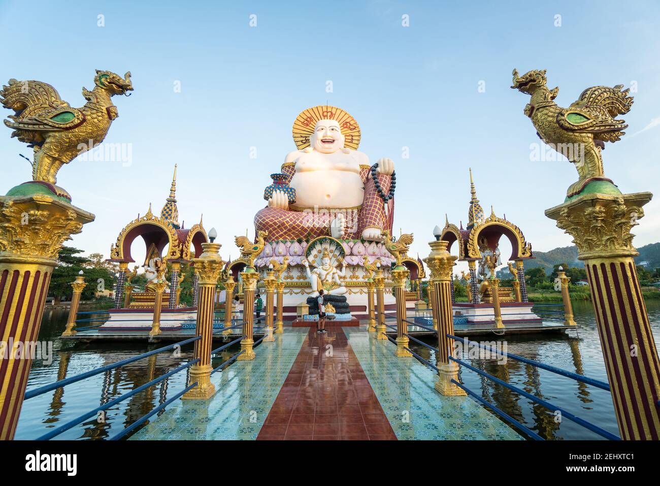 KOH SAMUI, THAILAND - 10. Januar 2020: Mann mit Kamera steht auf einer Brücke zu einer riesigen, farbenfrohen buddha-Statue am Wat Plai laem-Tempel auf koh samui Stockfoto