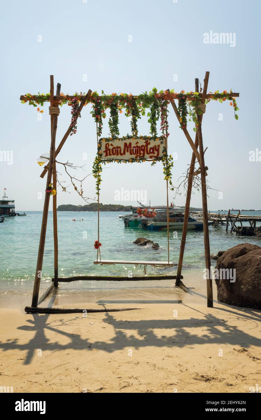 Schaukeln Sie am Strand auf der Fingernagel-Insel mit der Holztafel, die den Namen der Insel auf vietnamesisch (Hon Mong Tay), Vietnam, zeigt Stockfoto