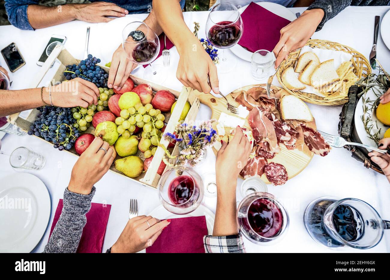 Draufsicht auf die Hände von Freunden, die Essen und Wein essen Grillgartenparty - Gruppen genießen Obst und Scheiben Würste im Hinterhof Meeting Stockfoto