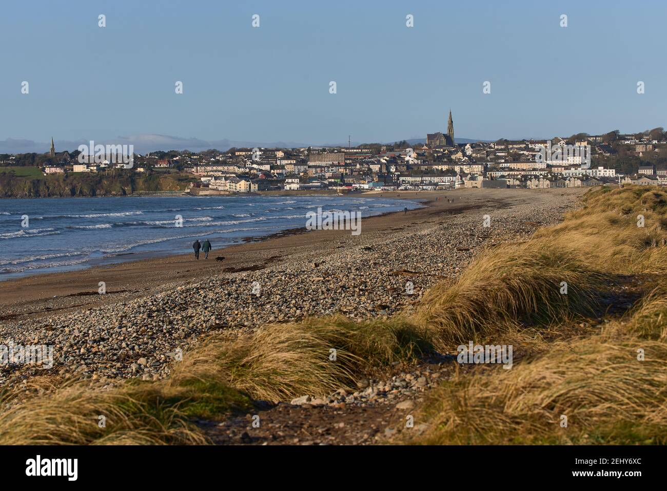 Irischer Strand mit Stadt im Hintergrund mit katholischer Kirche auf dem Berg. Tramore Naturschutzgebiet. Waterford. Irland. Landschaft Stockfoto