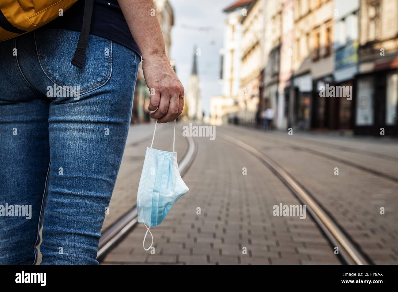 Neues normales Hotel an einer leeren Straße. Tourist Frau hält Gesichtsmaske in der Hand. Reise- und Tourismuskonzept während der Coronavirus-Pandemie Stockfoto