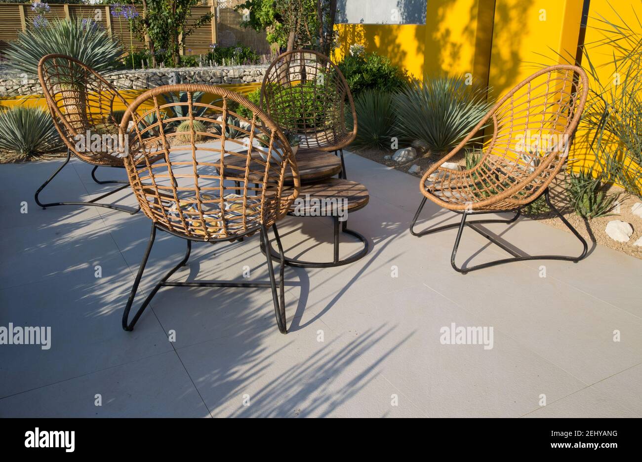 Moderner, grauer, moderner, aus Stein gemauerte Sitzbereich im Gartendesign mit Tisch und Rattanrohrstühlen in einem modernen mediterranen Garten in Großbritannien Stockfoto