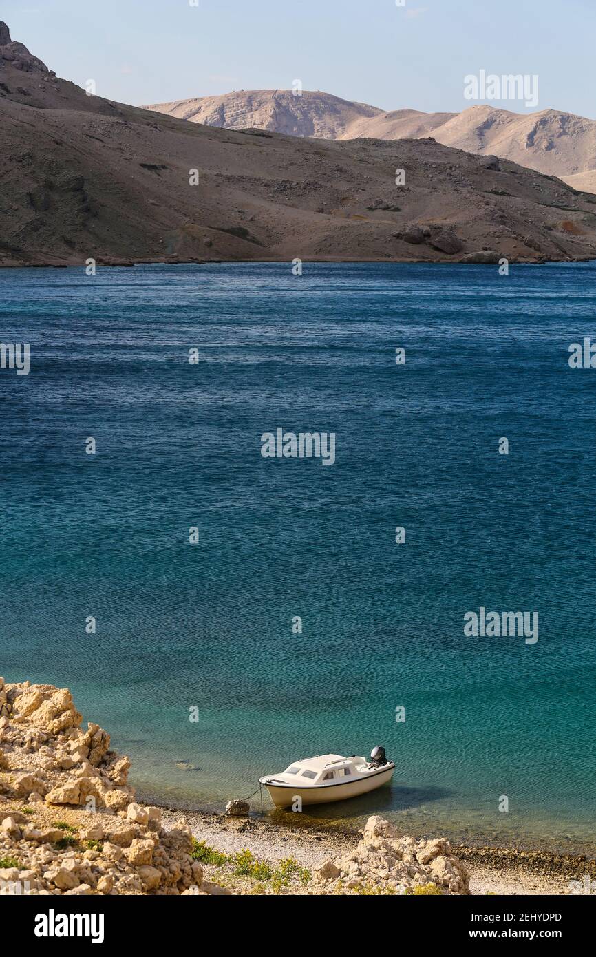 Ein Boot dockte in EINER Bucht von einem Rocky Beach an In Insel Pag und Meer im Hintergrund Stockfoto