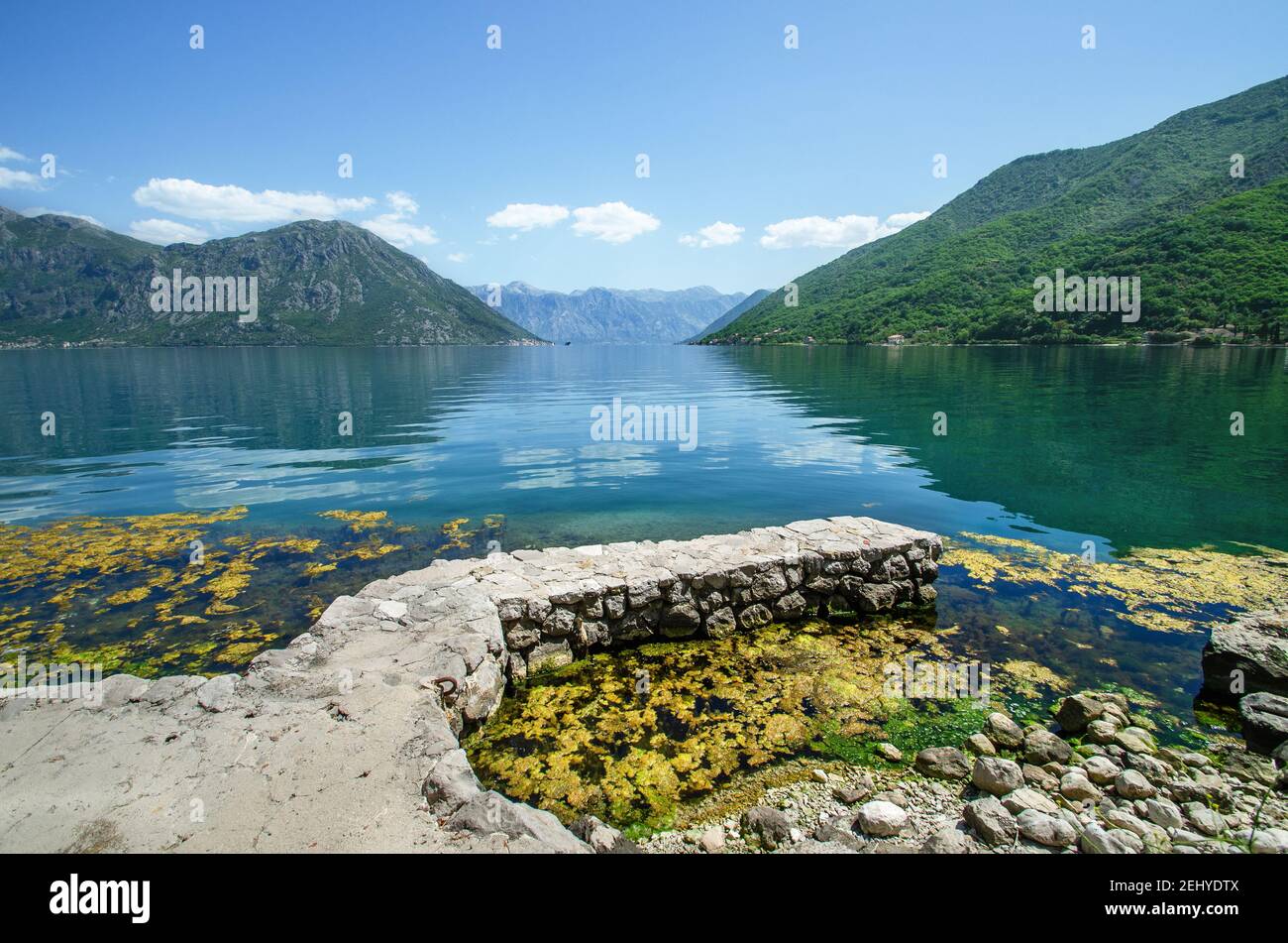 Blick auf die Bucht von Kotor mit Reflexionen der Berge und Steinpier, Blick auf Perast und Kostanijca, Montenegro von Flavia Brilli Stockfoto