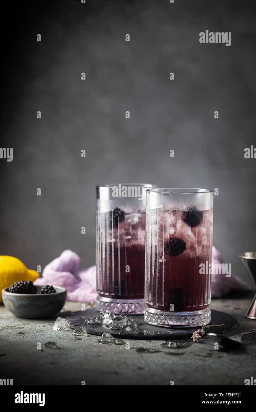 Erfrischende Blackberry Lemonade mit Eis in Kristallgläsern auf grauem Hintergrund Stockfoto