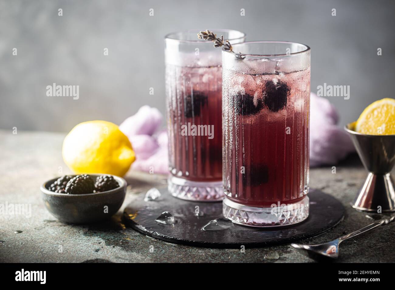 Erfrischende Blackberry Lemonade mit Eis in Kristallgläsern auf grauem Hintergrund Stockfoto