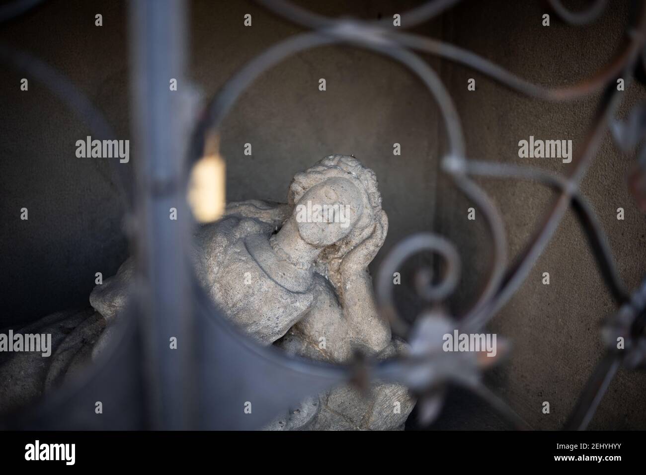 Statue und Skulptur von Frau, Frau und Mädchen ist hinter den Bars versteckt. Figurine kontempliert und träumt mit geschlossenen Augen. Sehr geringer Fokus. Stockfoto