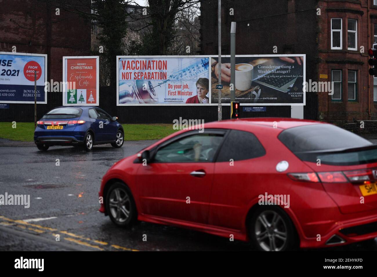 Greenock, Schottland, Großbritannien. 20. Februar 2021. Im Bild: Bild der schottischen First Minister, Nicola Sturgeon mit Grafik von einem COVID19 Impfstoff und einer Spritze mit dem Slogan, “IMPFUNG NICHT TRENNUNG. MACHEN SIE IHRE ARBEIT, ERSTER MINISTER.“ auf einer Plakatwand mitten in Greenock an einer geschäftigen Kreuzung der Brougham St & Campbell St. Dies bezieht sich auf die stille Mehrheit der Menschen in Schottland, die sich gegen die SNP wehren und versuchen, ein zweites Unabhängigkeitsreferendum inmitten einer Pandemie zu erreichen Im Vereinigten Königreich wurden über 106.000 Menschen getötet, davon allein 6.816 in Schottland. Quelle: Colin Fisher/Alamy Live News. Stockfoto