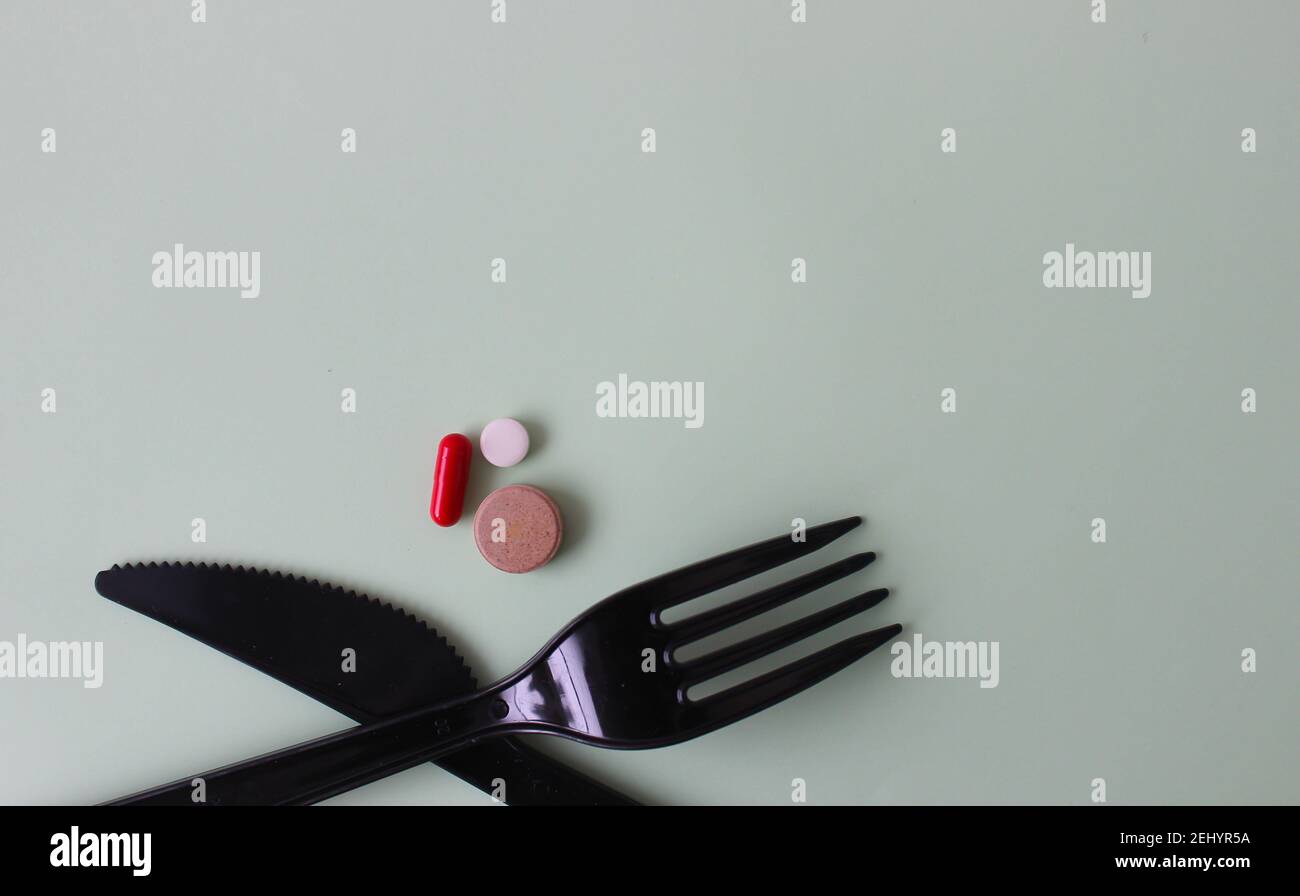 Schwarzes Besteck mit farbigen Tafeln. Messer mit Gabel und Tabletten auf farbigem Hintergrund. Stockfoto