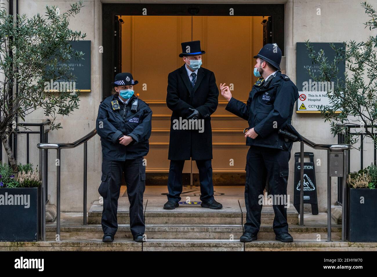 London, Großbritannien. Februar 2021, 20th. Die Polizei und ein Türsteher in einem Hut bewachen die Eingangstür - seine Königliche Hoheit der Herzog von Edinburgh (Prinz Philip) wurde am Dienstagabend im King Edward VII Hospital in Marylebone London eingeliefert. Er wurde offenbar nicht für Covid Gründen trotz National Lockdown 3 weiterhin außerhalb zugelassen. Kredit: Guy Bell/Alamy Live Nachrichten Stockfoto