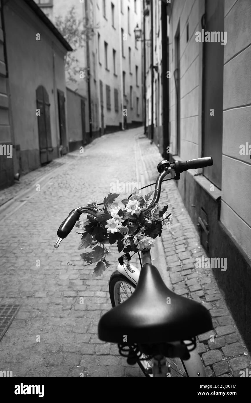 Fahrrad mit kleinen Blumenstrauß an der Griffstange in der alten Straße, der Altstadt von Stockholm, Schweden. Schwarz-Weiß-Stadtfotografie Stockfoto