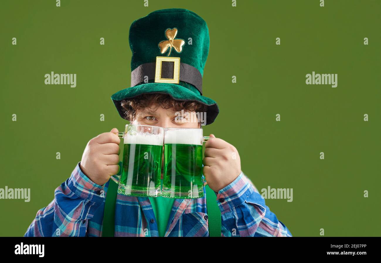 Fröhlicher Mann, der den St. Patrick's Day feiert und grünes Bier genießt Aus zwei großen Gläsern Stockfoto