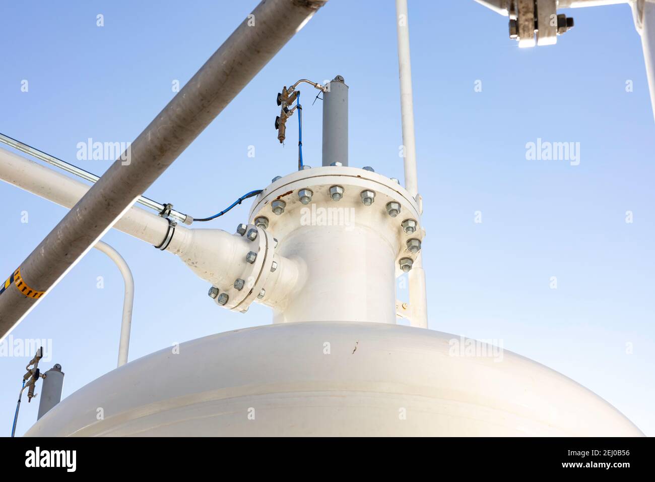 Industrieller Hintergrund mit Rohren, Verbindungen, Schrauben und Druckbehälter Farbe weiß mit blauem Himmel als Hintergrund Stockfoto