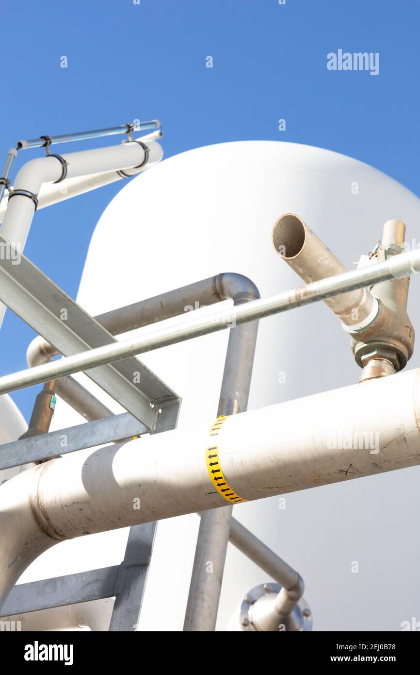 Industrieller Hintergrund mit Rohren, Verbindungen, Schrauben und Druckbehälter Farbe weiß mit blauem Himmel als Hintergrund Stockfoto