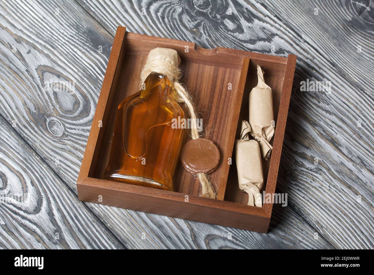 Geschenk Alkohol. Eine Flasche Alkohol und Süßigkeiten befinden sich in  einer Holzkiste Stockfotografie - Alamy