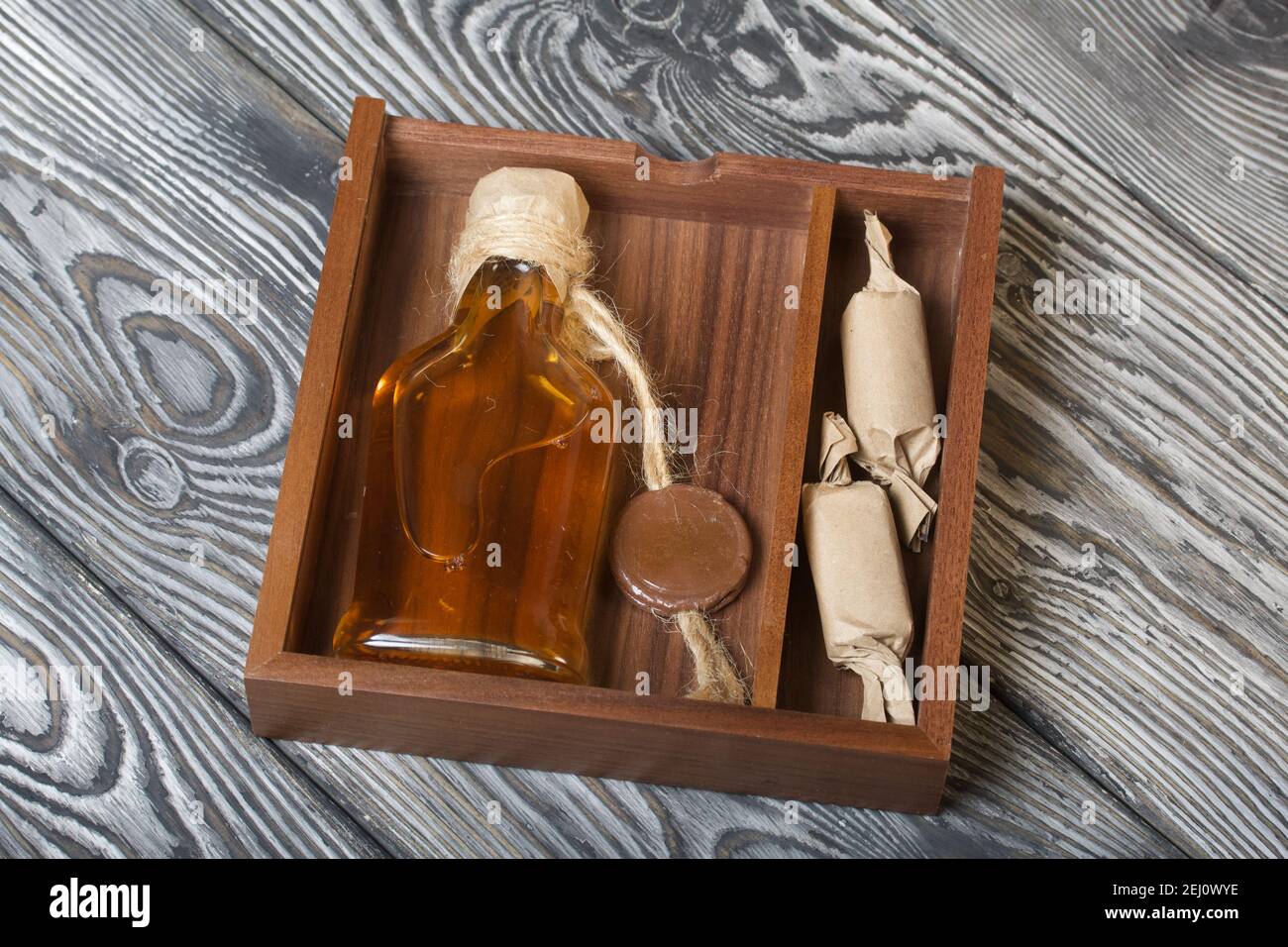 Geschenk Alkohol. Eine Flasche Alkohol und Süßigkeiten befinden sich in  einer Holzkiste Stockfotografie - Alamy