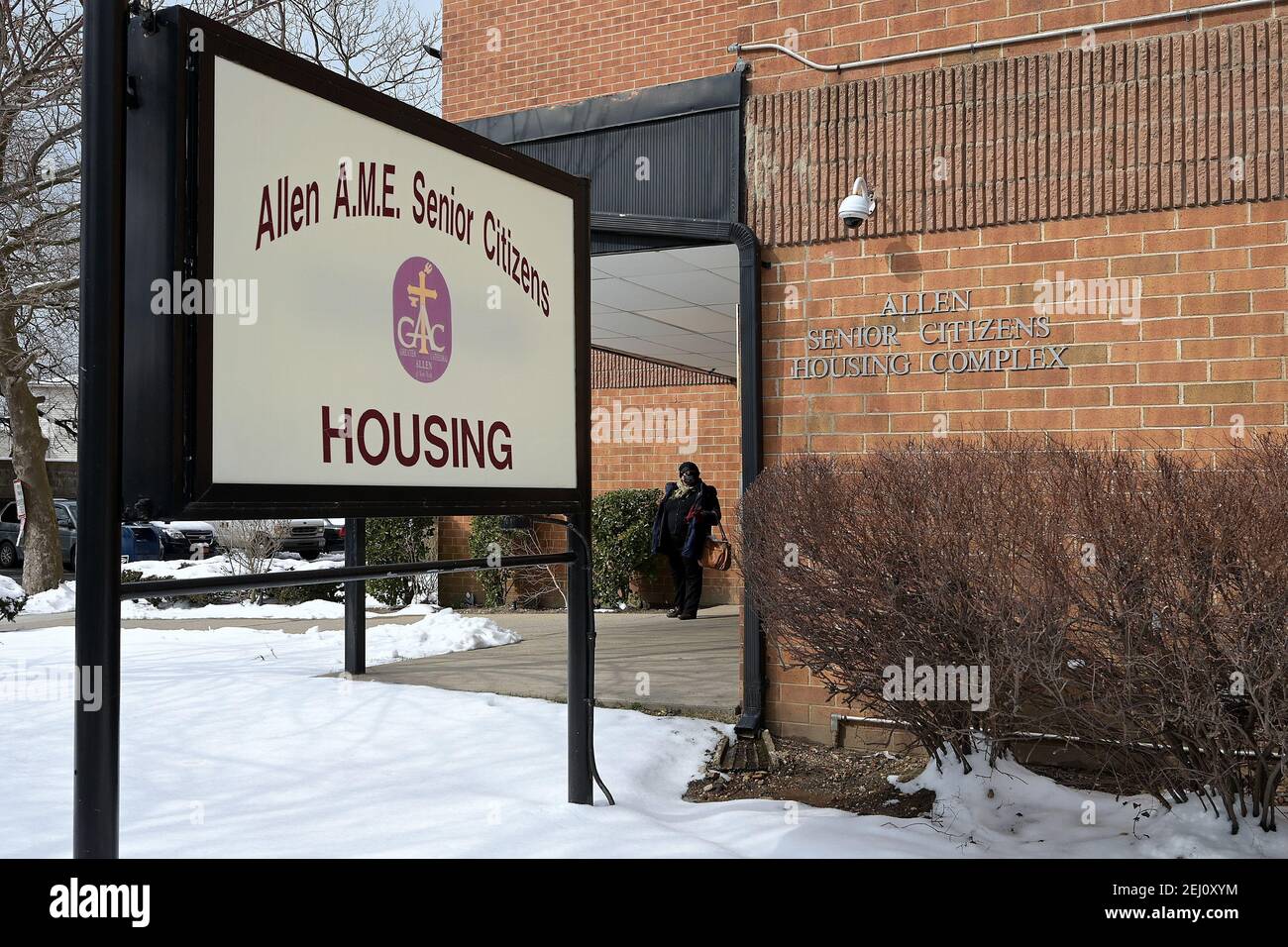 Eine Frau steht vor dem Allen Senior Citizens Housing Complex, wo ein