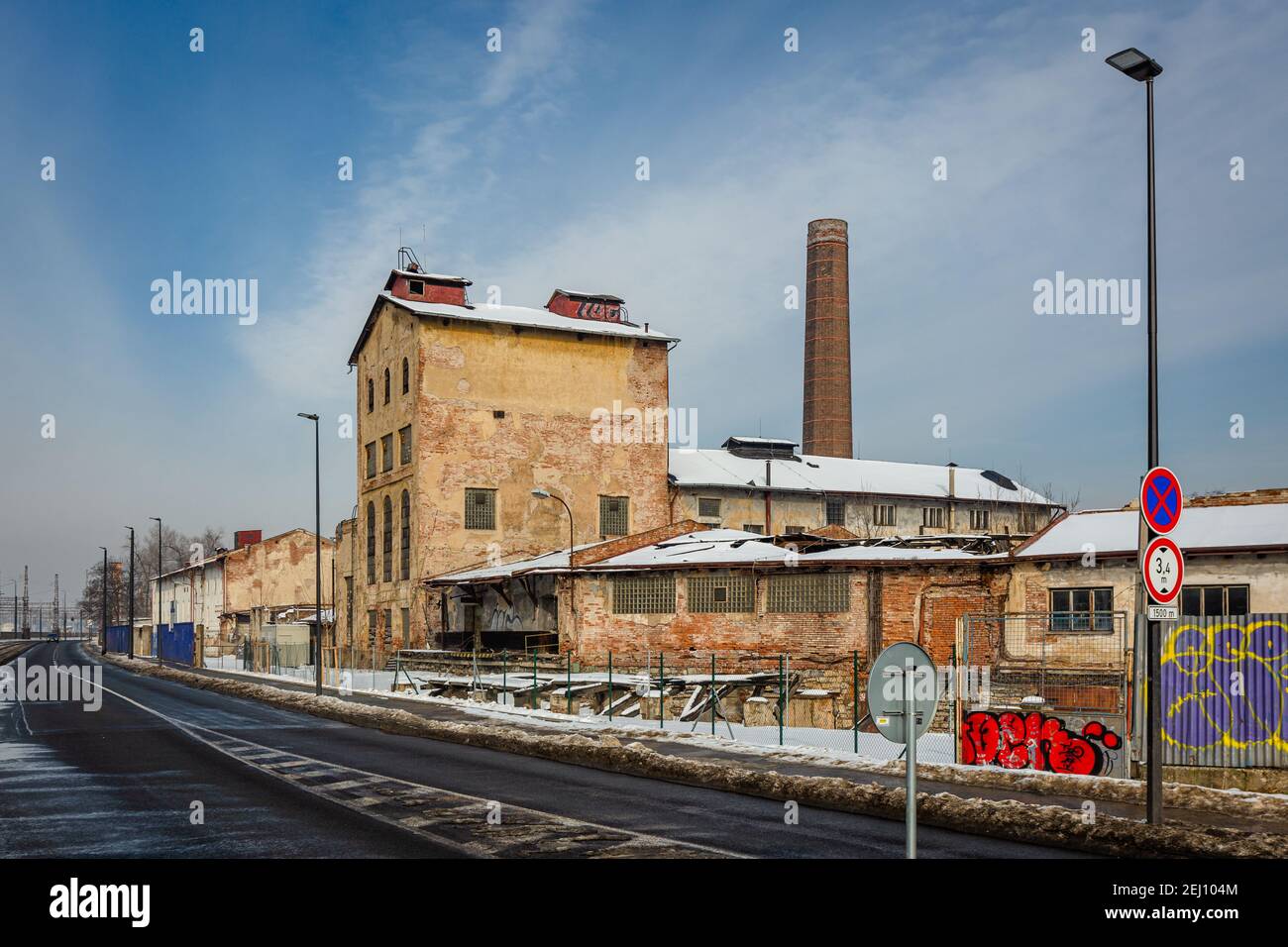 Prag, Tschechische Republik - Februar 16 2021: Ehemalige Brennerei namens Lihovar, ein zerstörtes Gebäude aus Ziegelsteinen, ein Kamin und eine Straße mit Verkehrsschildern Stockfoto