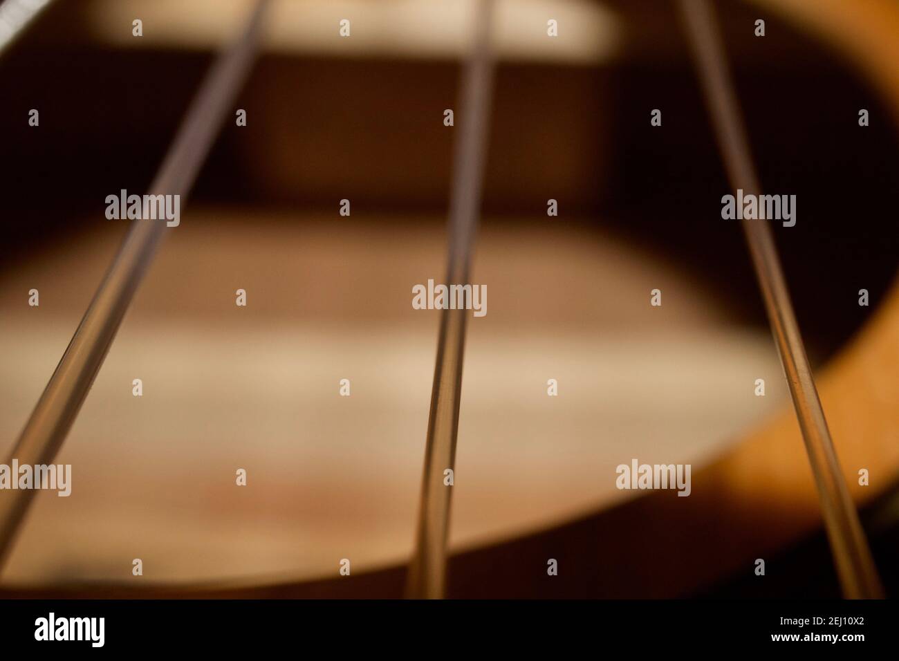Nahaufnahme von Gitarrensaiten, die direkt über dem Klangloch einer akustischen klassischen Gitarre aufgenommen wurden. Es zeigt das Innere der Gitarre. Stockfoto