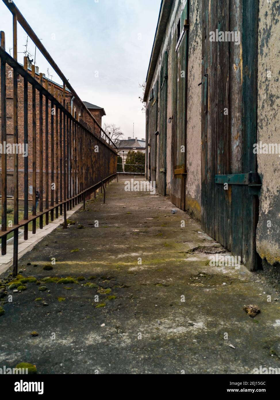 Langer Betonbalkon zwischen Metallgeländer und alten Holztüren Stockfoto