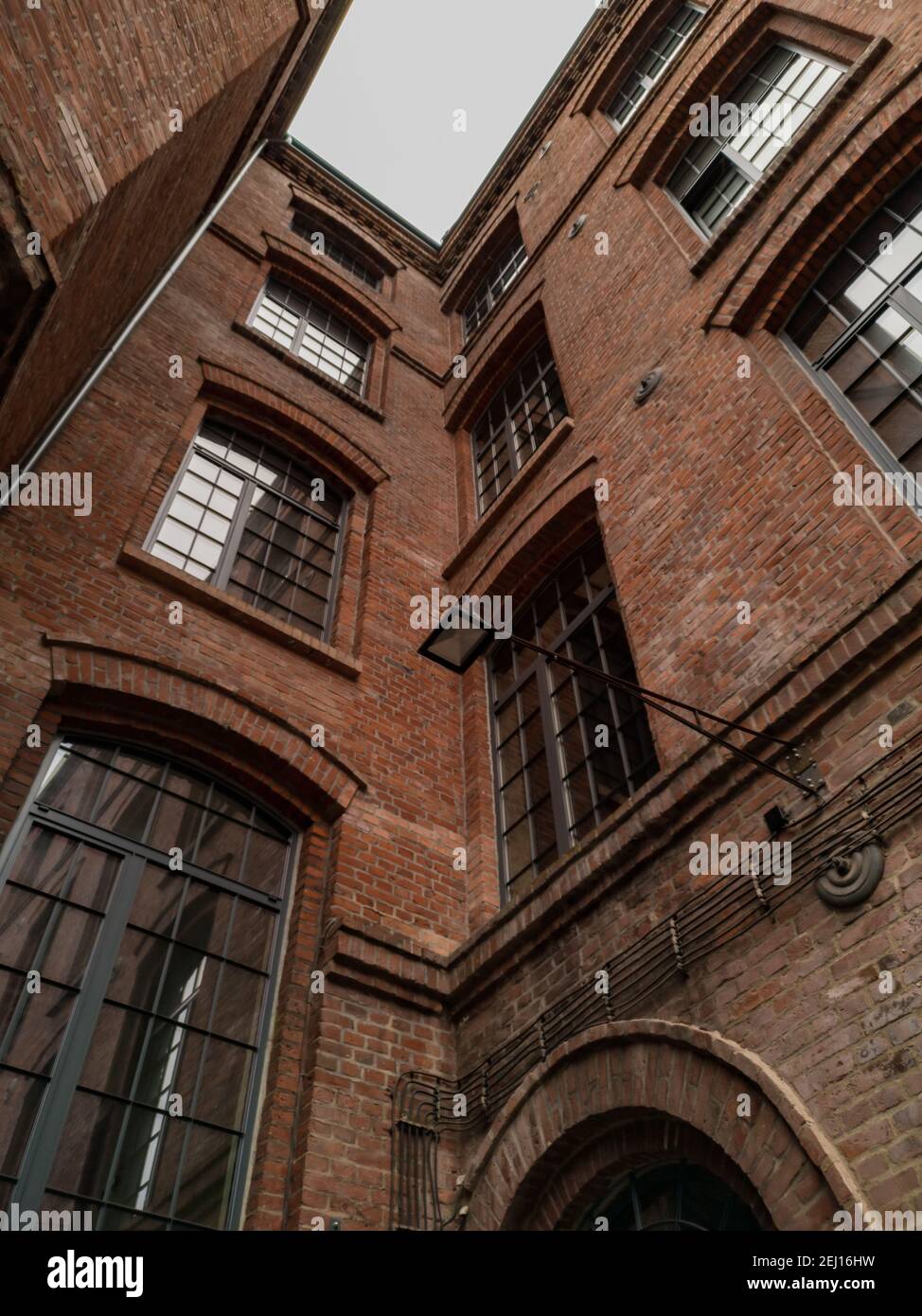 Blick nach oben auf das hohe Gebäude rote Ziegelmauer mit großen fenster Stockfoto