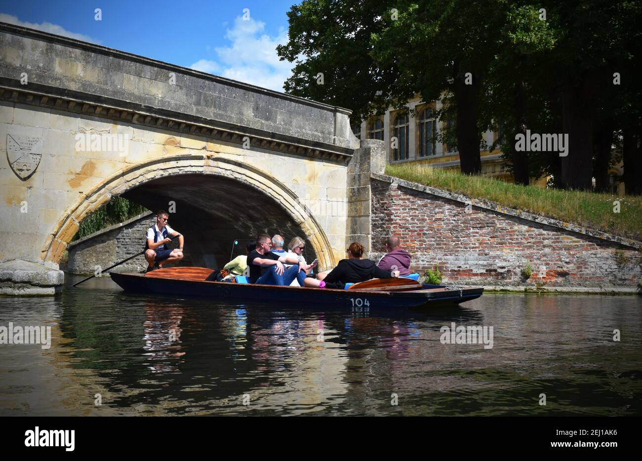 Ein Punter hockt sich, als sie und ihre Punt von Touristen unter einer Brücke segeln. Stockfoto