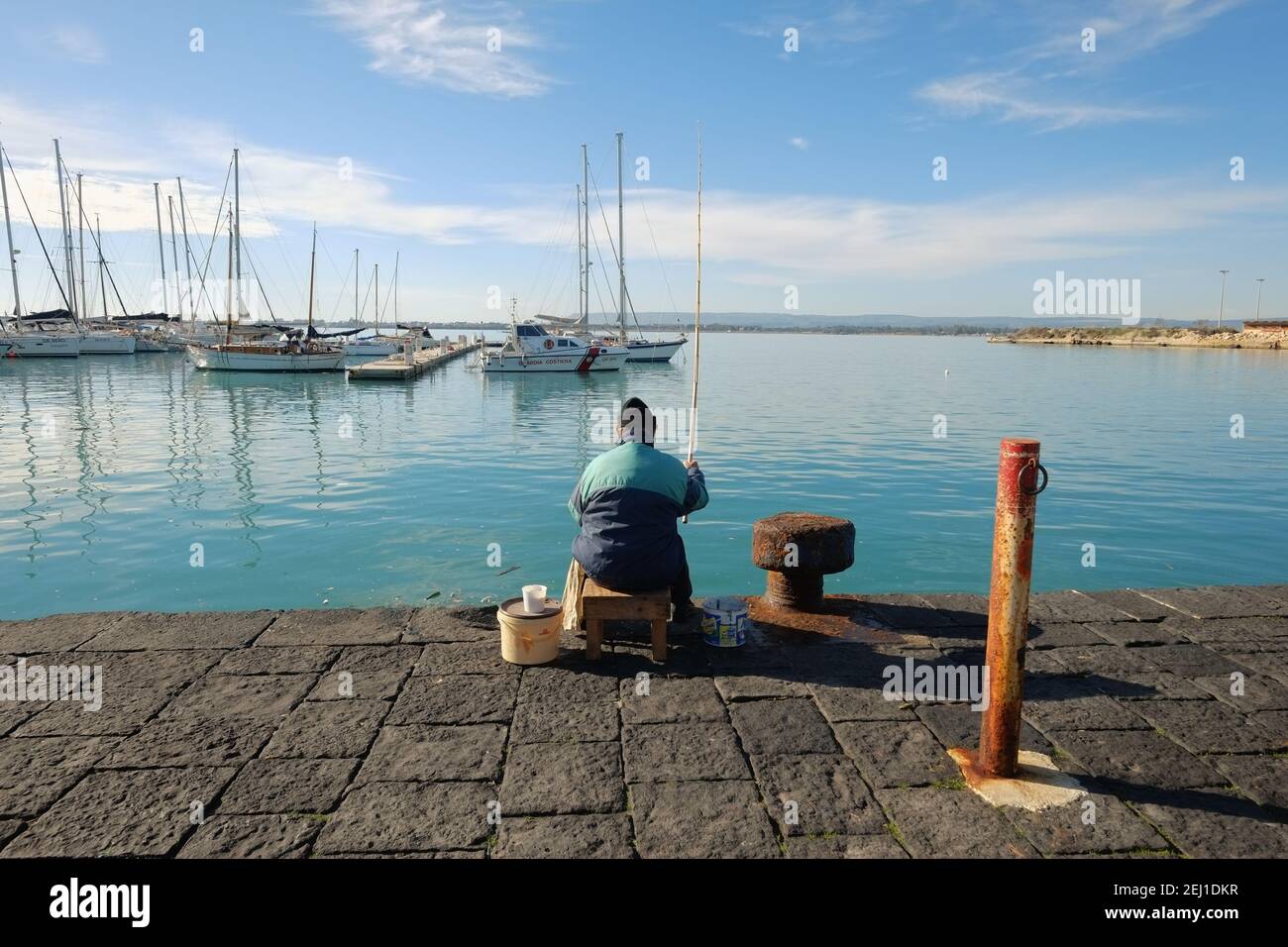 SIRACUSA, ITALIEN - JENUARY 03: Rückansicht des Mannes, der auf dem Pier von Ortigia sitzt und angeln, Altstadt von Siracusa. Sizilien. Aufgenommen 2015 Stockfoto