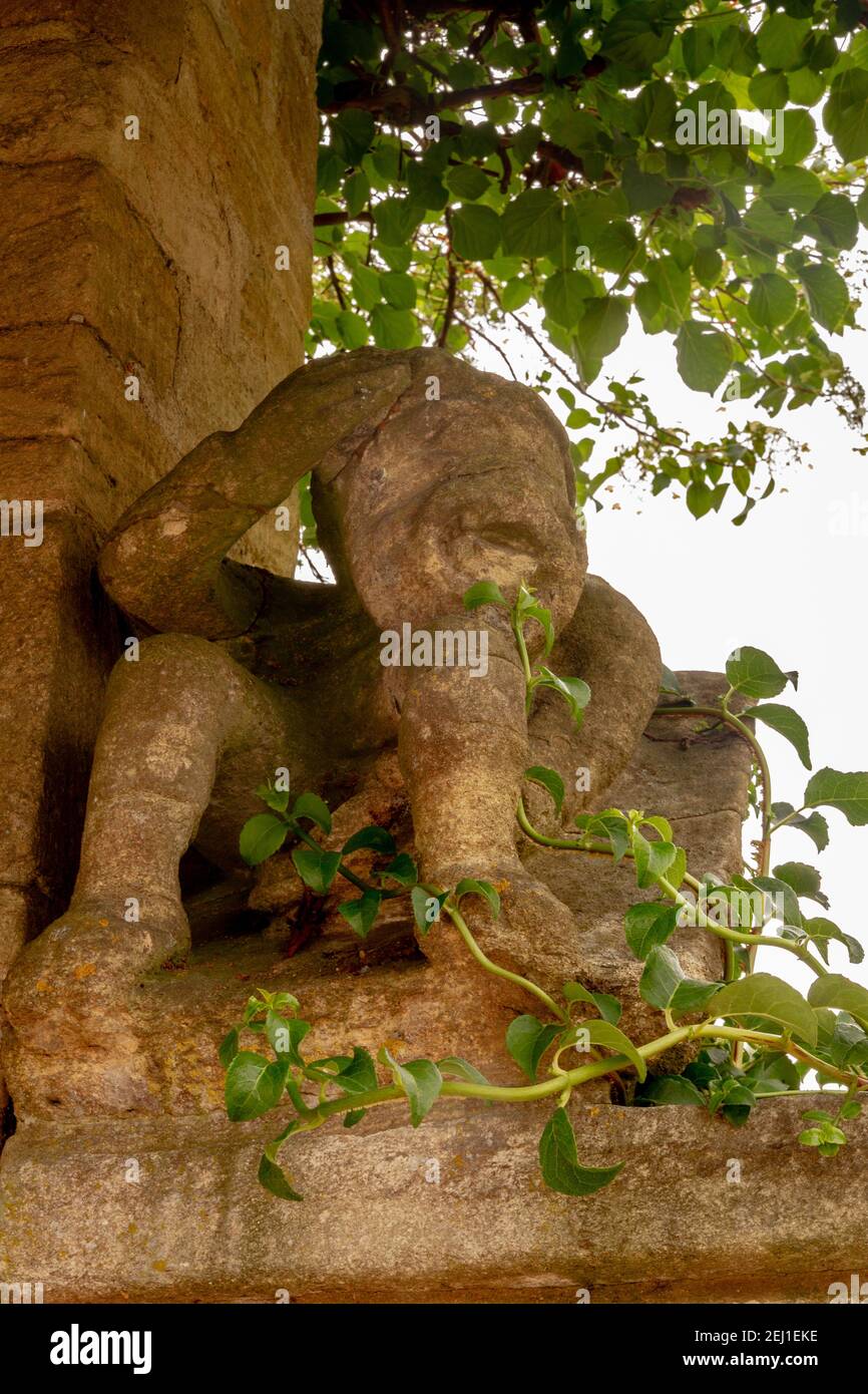 Alte Skulptur umgeben von Pflanzen Stockfoto