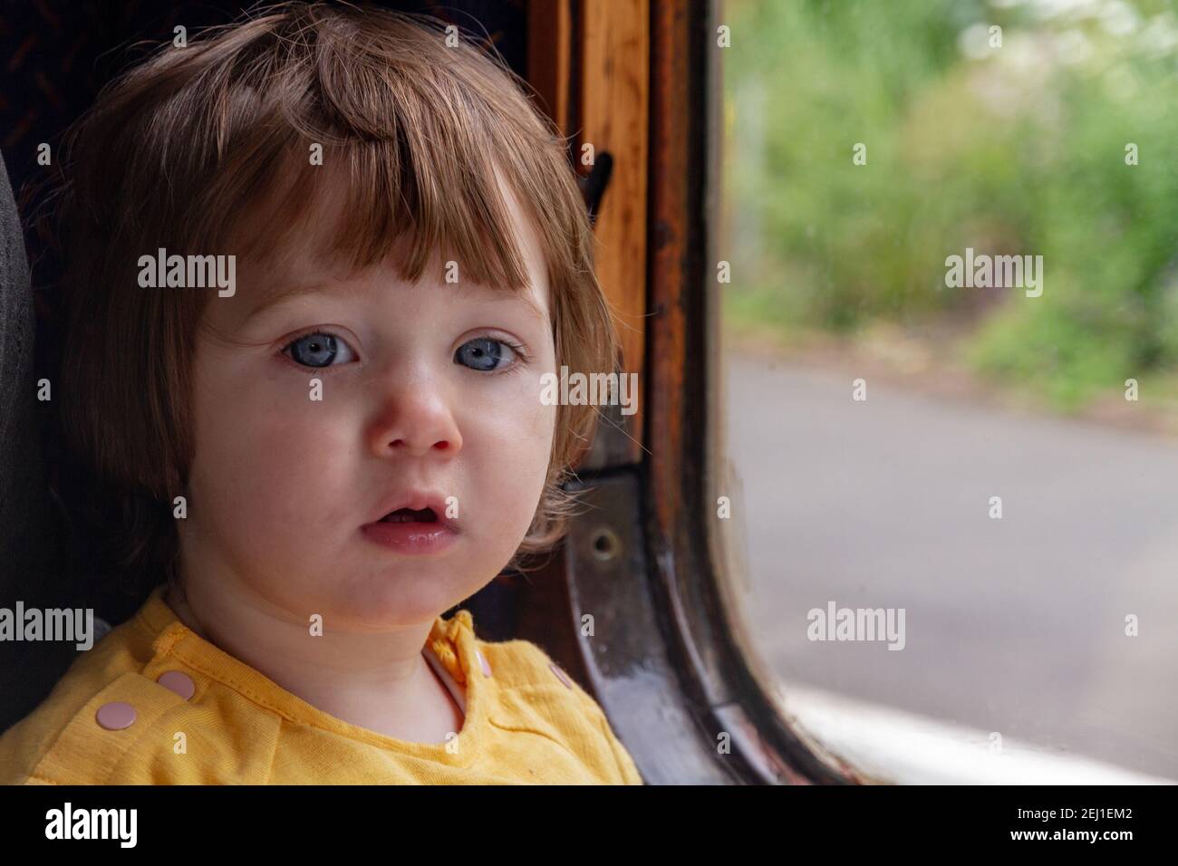 Baby Mädchen, das an einem Zugfenster sitzt Stockfoto