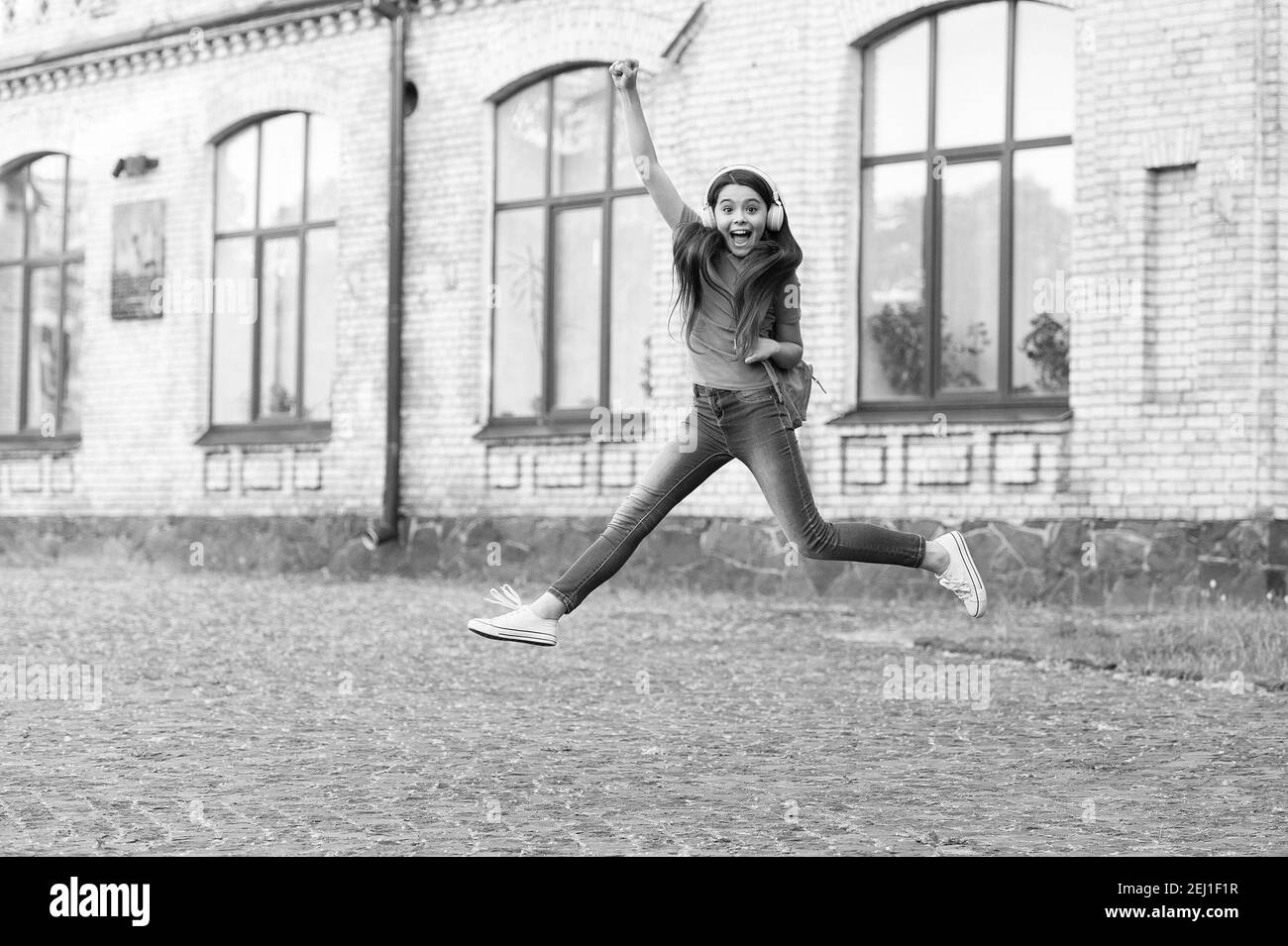 Energetische Kind Mädchen springen tanzen Musik Kopfhörer hören, nie aufhören Konzept. Stockfoto