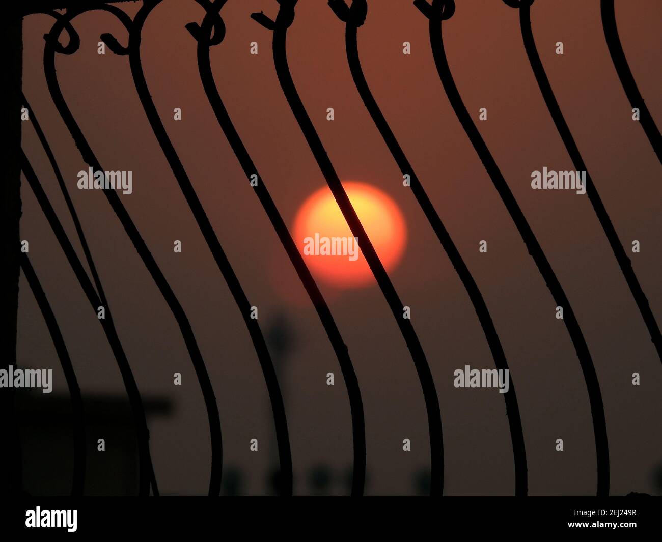 Selektive Fokus von Metall rustikalen Bars gegen den verschwommenen Himmel und Sonne während des Sonnenuntergangs, Silhouette Ansicht, Sonne hinter Bars Stockfoto