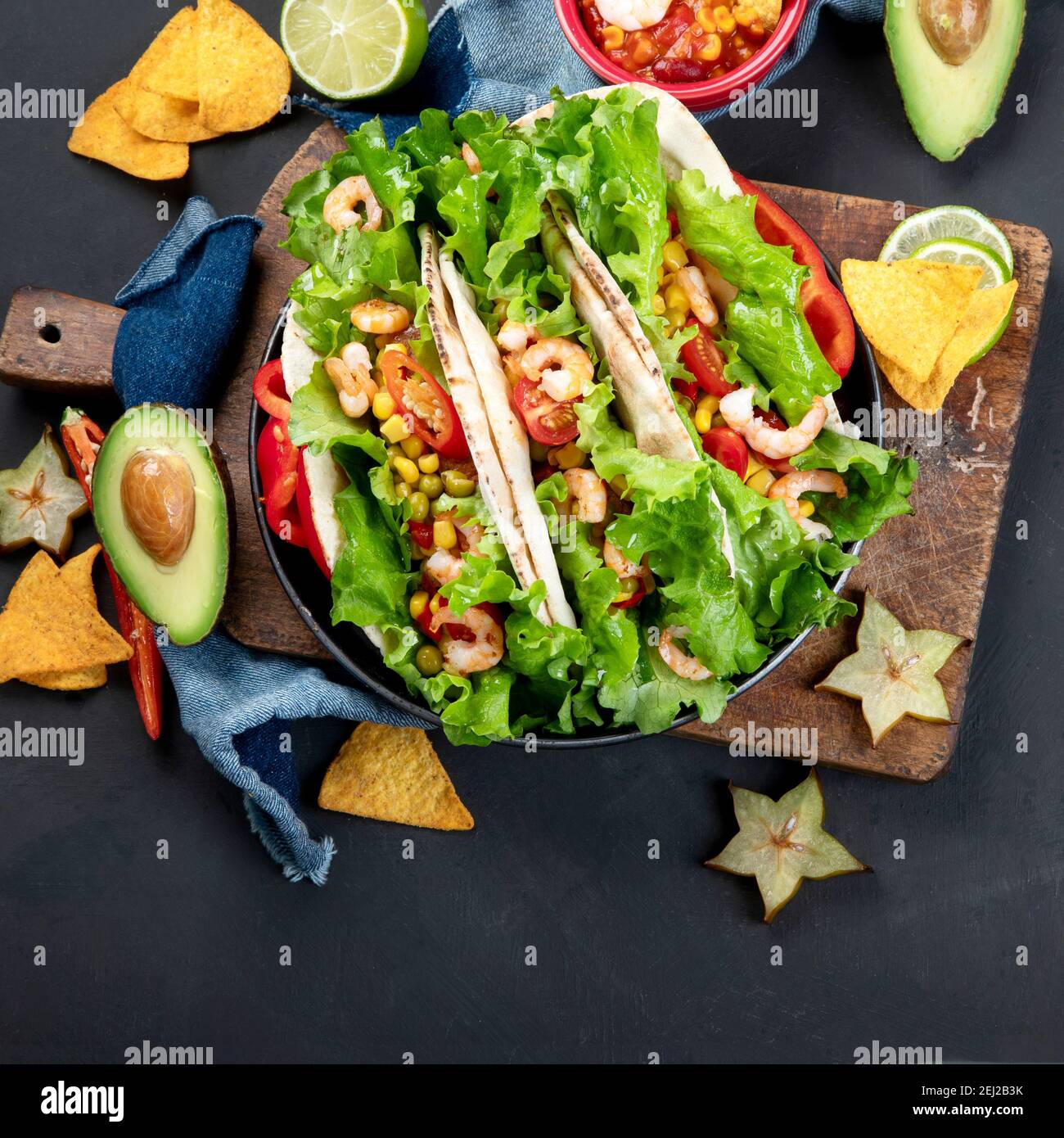 Köstliche hispanisch-mexikanische Speise-Tafel mit Tacos, Guacamole, Garnelen, Avocado und Starfruit. Scharf und würzig. Draufsicht Stockfoto