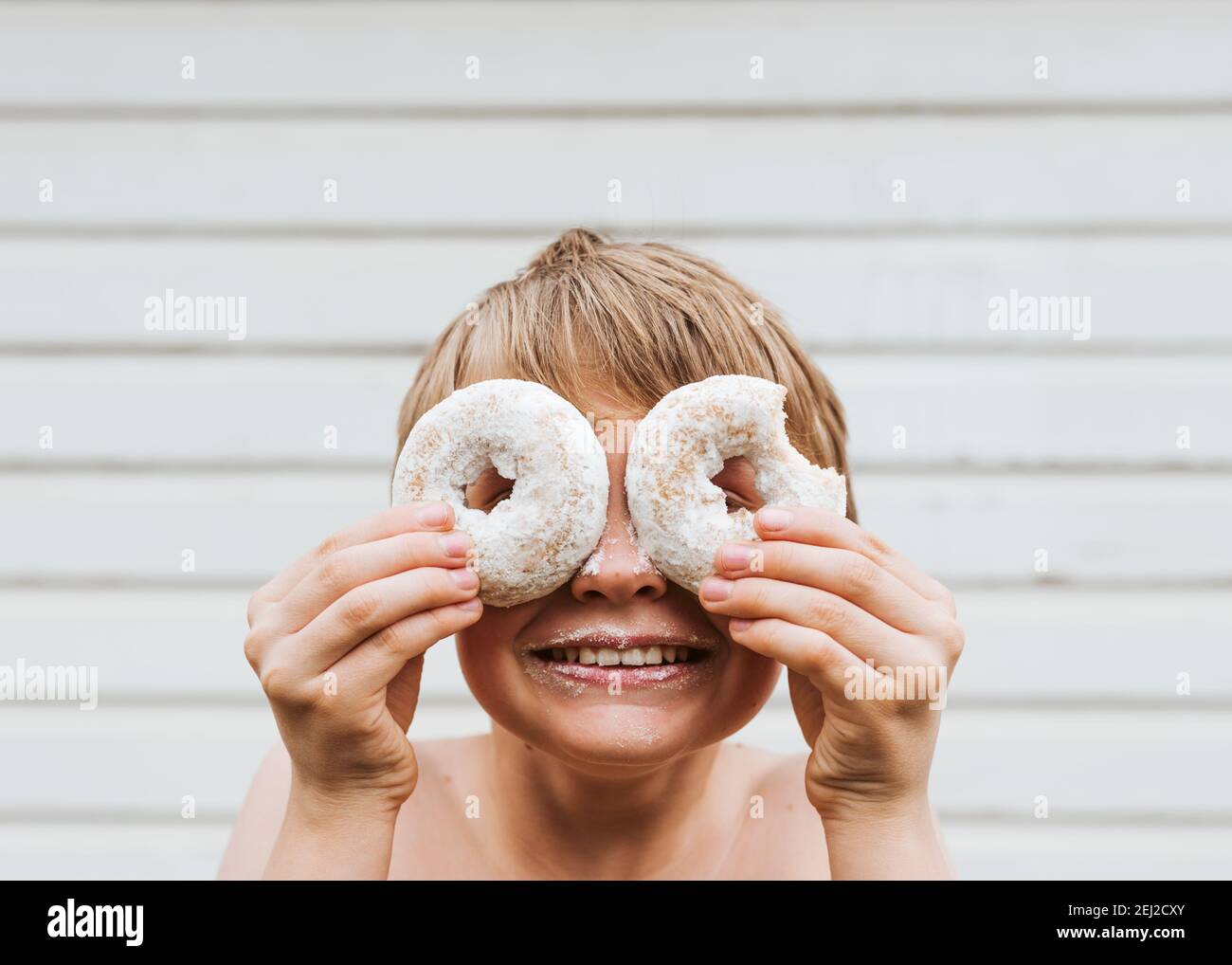Mein Sohn hielt Donuts an seine Augen und sah durch die Löcher in der Mitte. Stockfoto
