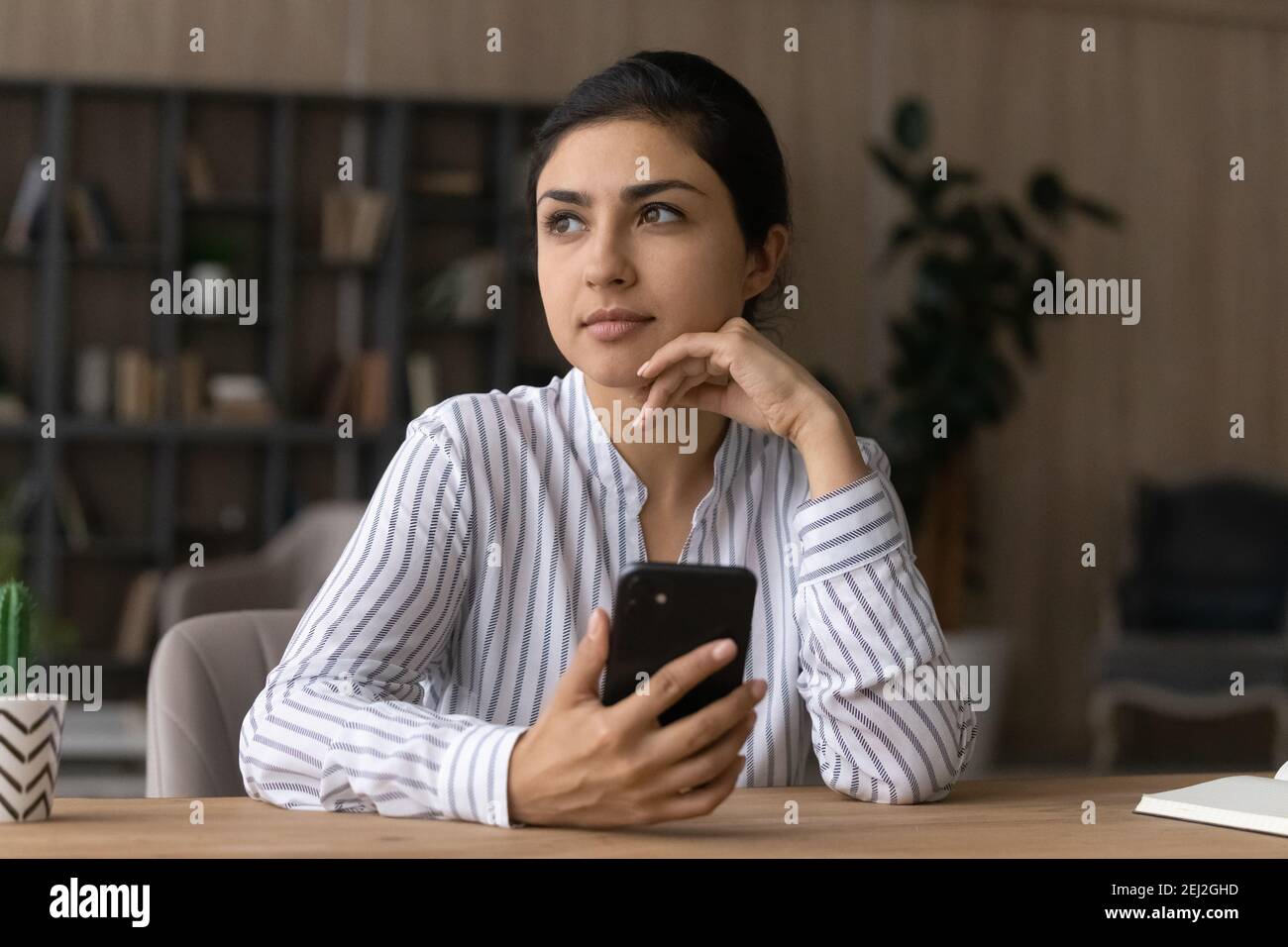 Nachdenkliche indische Frau verwenden Handy-Gadget Nachdenken Stockfoto