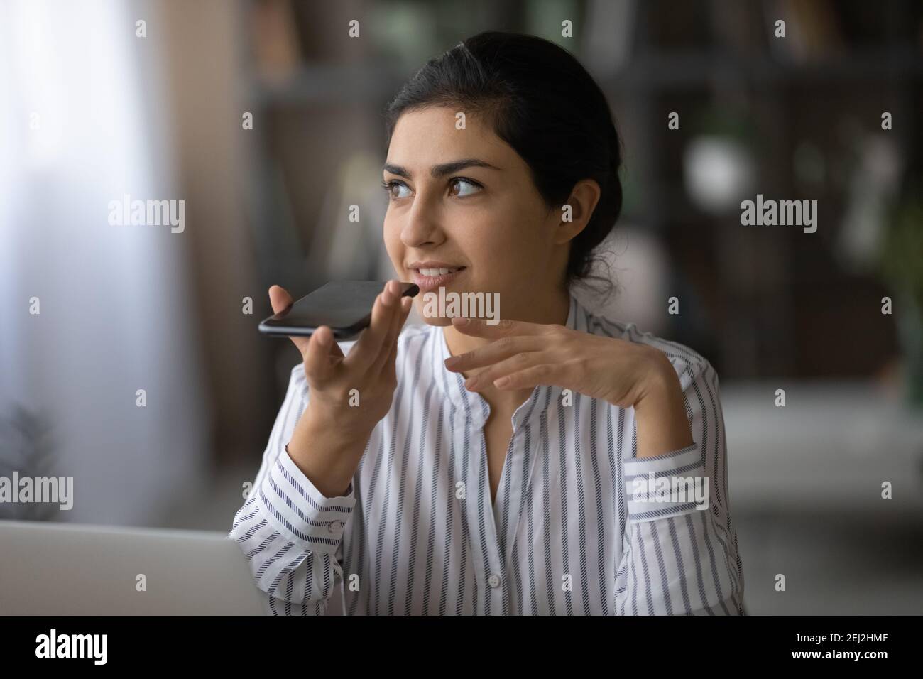 Millennial Indian Frau aktivieren digitalen Sprachassistenten auf Handy Stockfoto