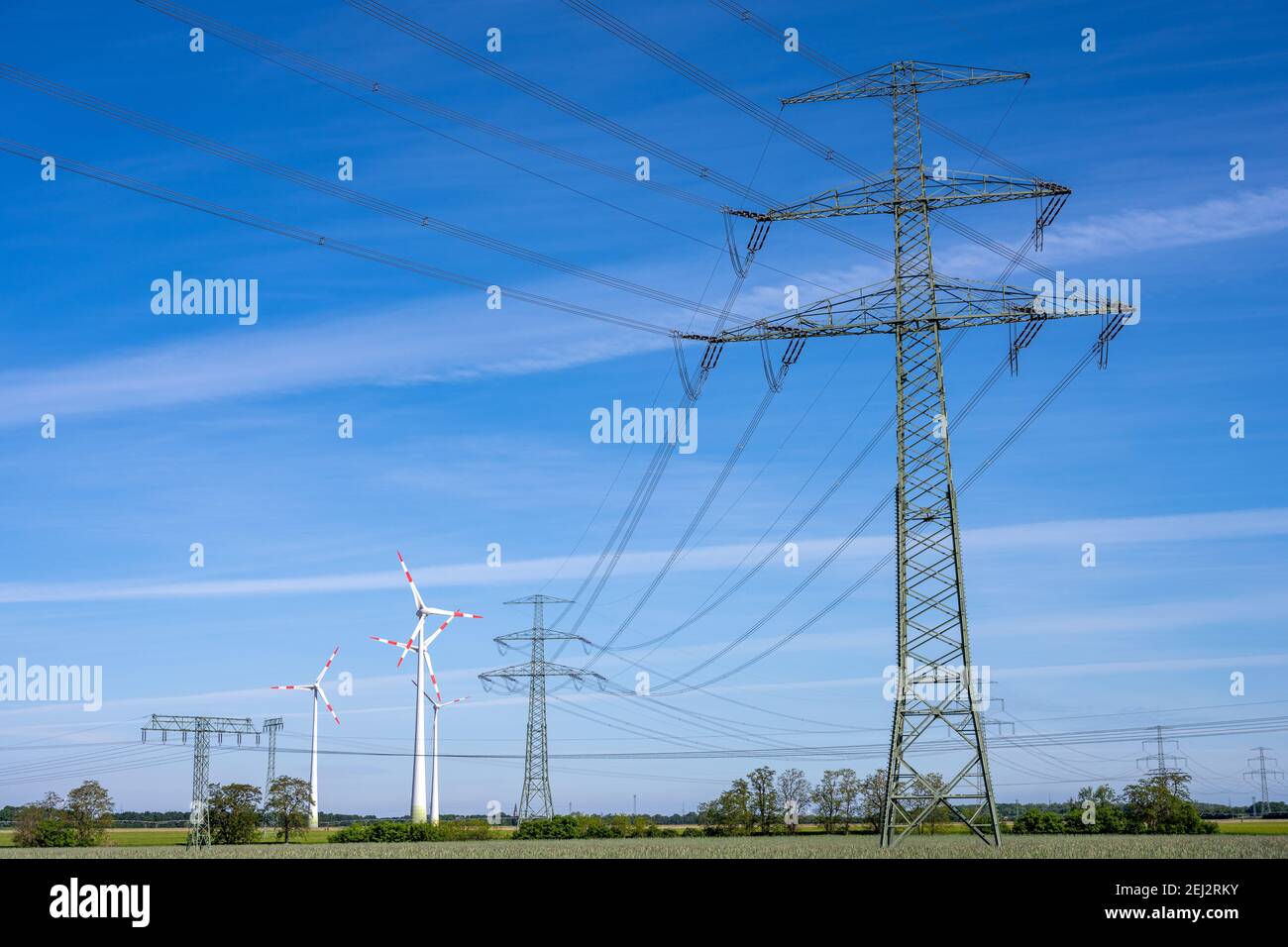 Strompylon und Stromleitungen mit Windturbinen in der Hintergrund Stockfoto