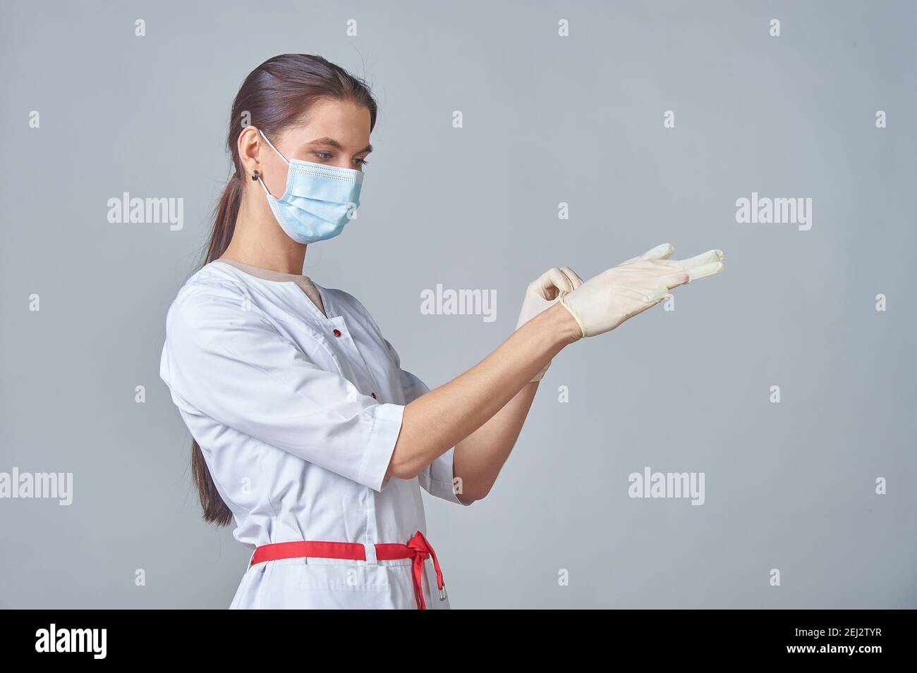 Eine Krankenschwester in einer medizinischen Maske trägt medizinische Handschuhe in Ein weißes Fell Stockfoto