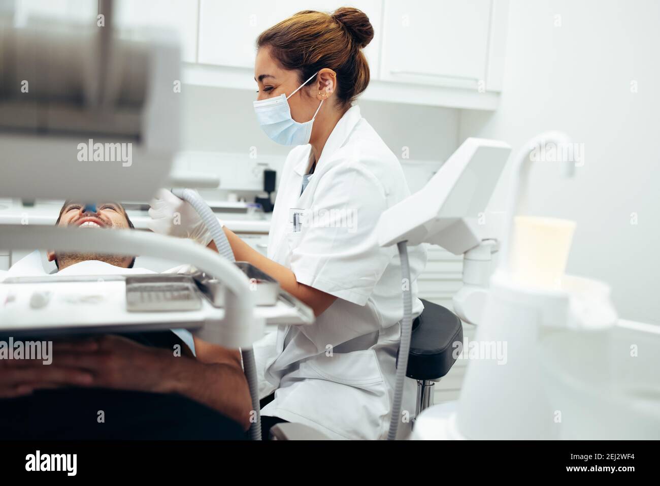 Weibliche Zahnärztin, die die Zähne eines männlichen Patienten untersucht. Zahnarzt mit Werkzeugen, um die Zähne eines Mannes im Zahnarztstuhl sitzen / zu überprüfen Stockfoto