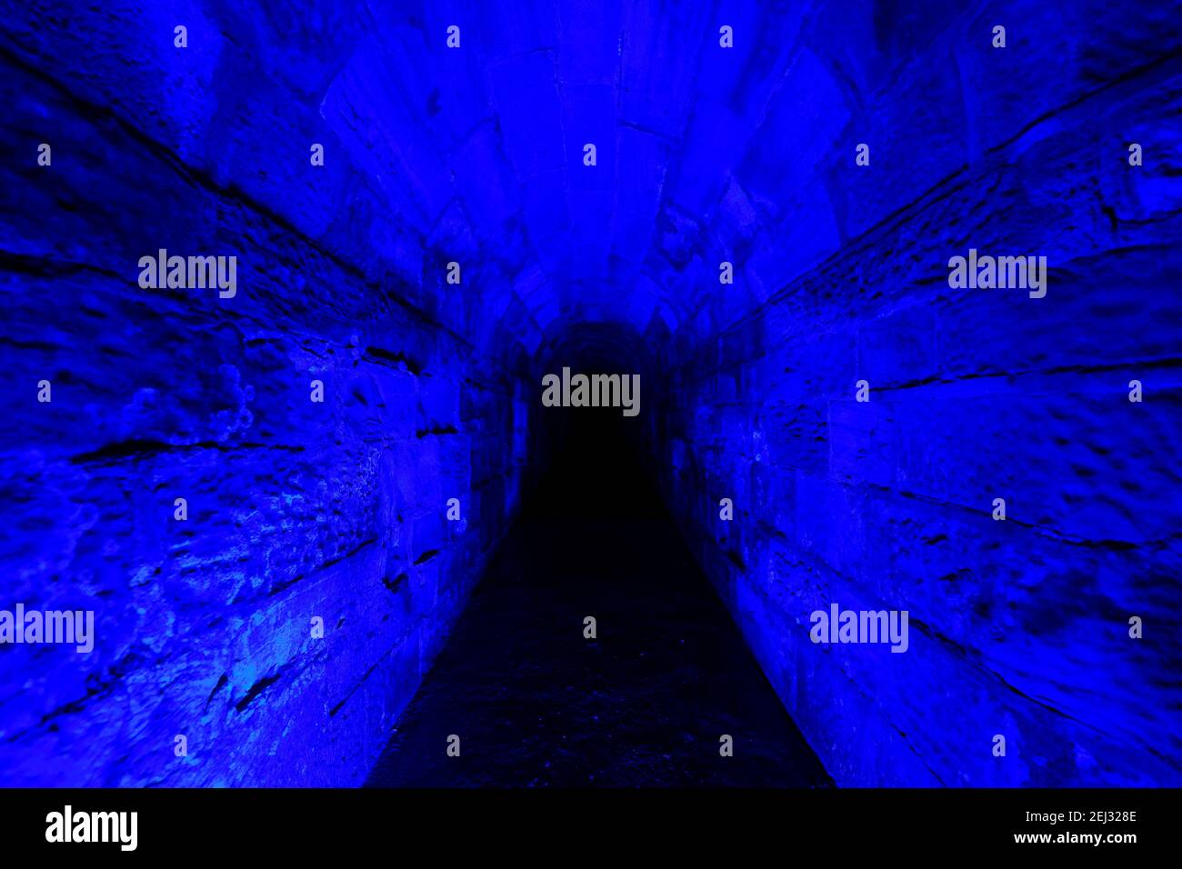 Ein Wasserüberlauftunnel aus einem See bei Temple Newsam in Leeds. Der Tunnel wurde mit einem RGB-Handlicht beleuchtet. Stockfoto