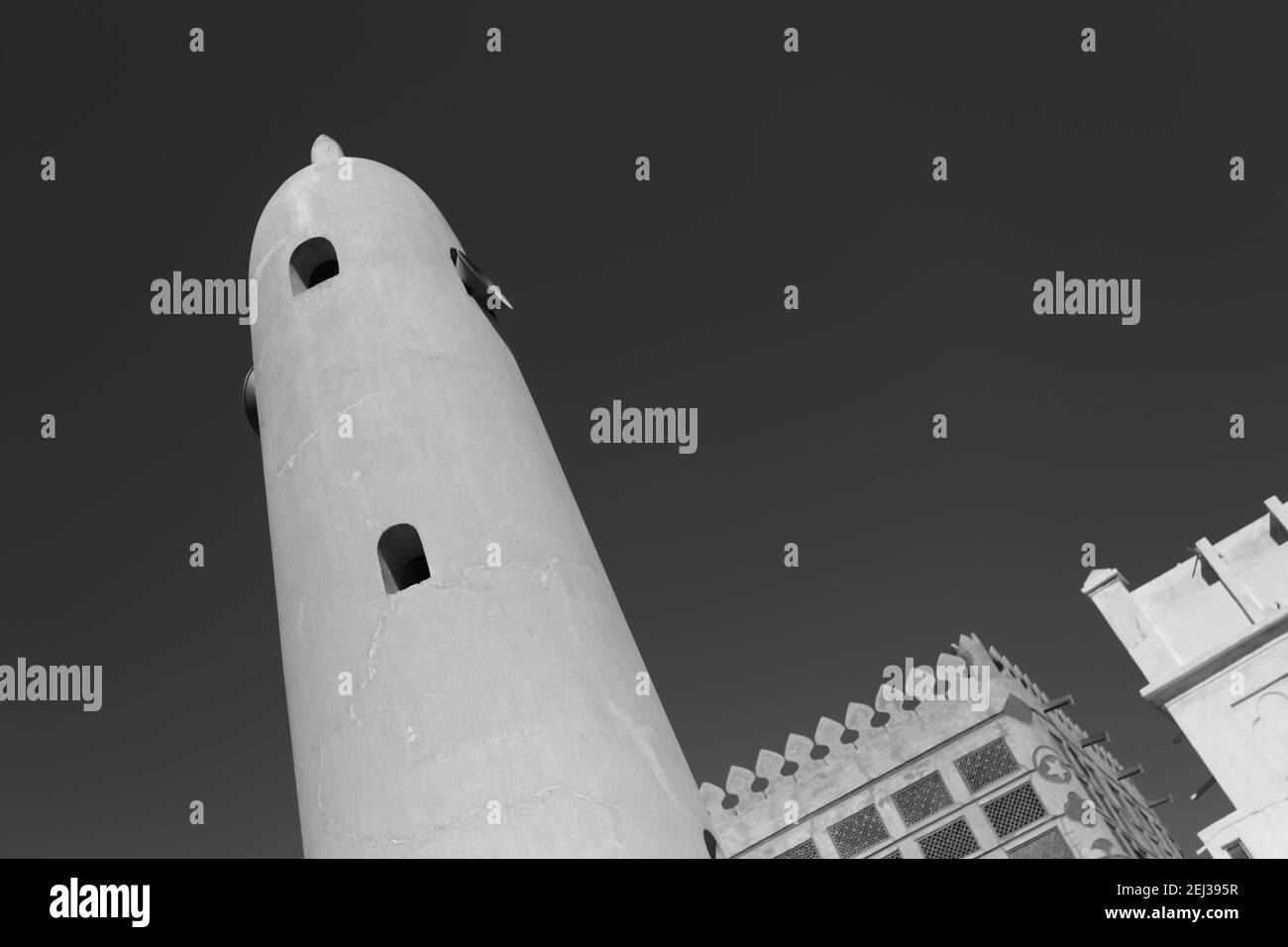 Einfarbiges, schwarz-weißes Bild des Minaretts der Siyadi-Moschee, des Siyadi-Hauses (Beit Siyadi) dahinter, auf dem Pearl Trail, Muharraq, Bahrain Stockfoto