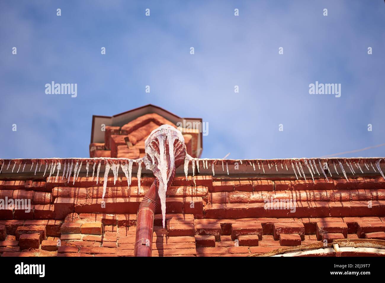 Eiszapfen auf Dächern an einem sonnigen Februartag Stockfoto