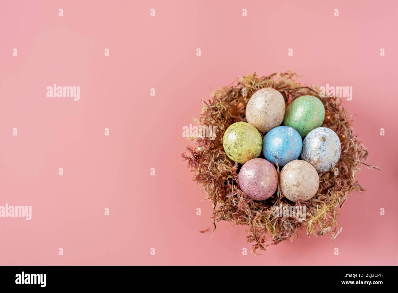 Ostereier in einem natürlichen Nest mit Moos auf einem rosa Hintergrund. Blick von oben. Stockfoto