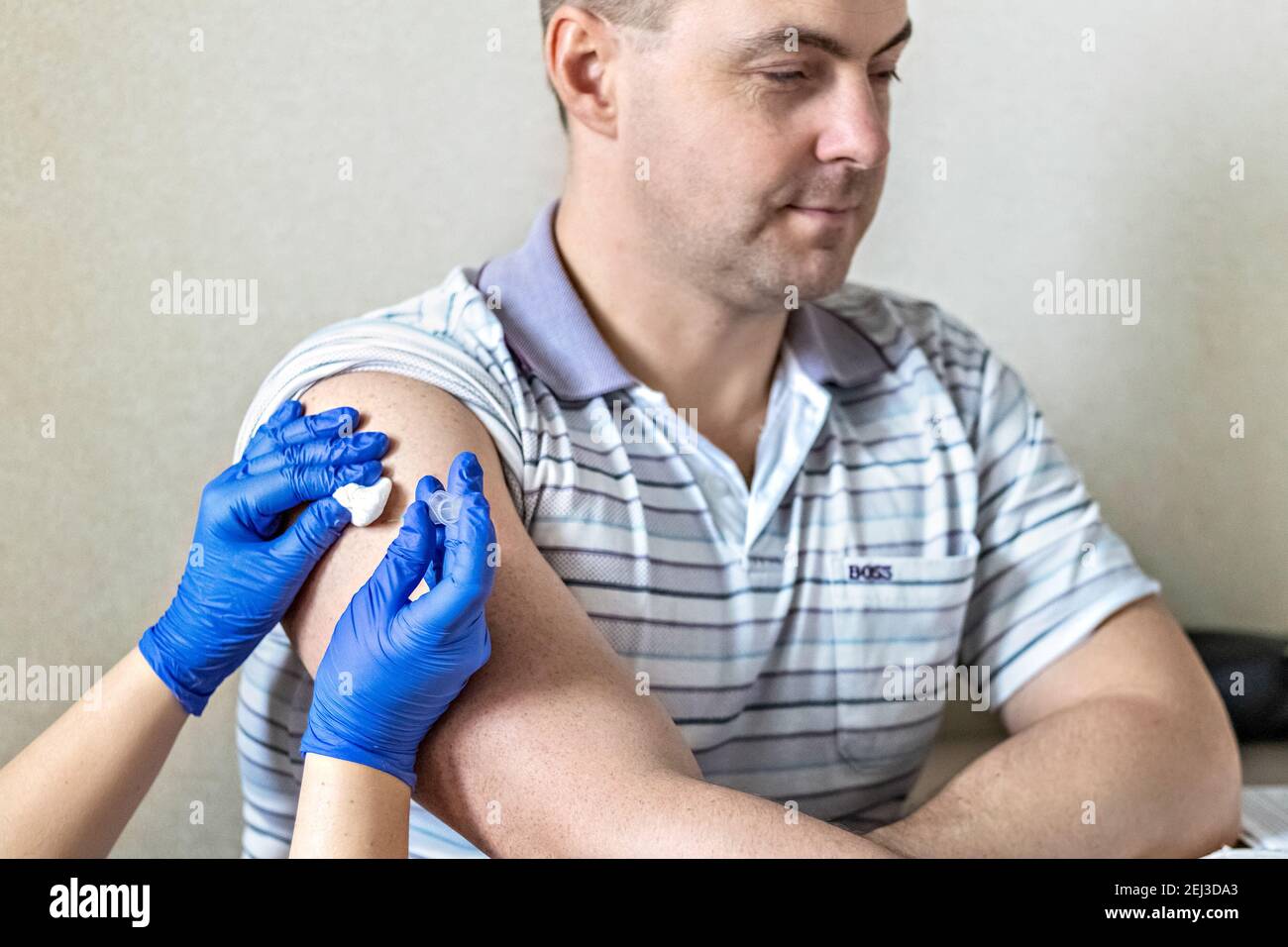 Ein Arzt impft einen Mann gegen Coronavirus in einer Klinik. Nahaufnahme. Das Konzept der Impfung, Immunisierung, Prävention gegen Covid-19 Stockfoto