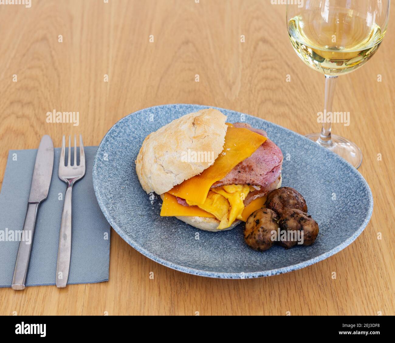 Einfaches Sandwich aus Schinken und amerikanischem Käse mit einer Seite von Pilzen gepaart mit einem Glas Weißwein. Stockfoto