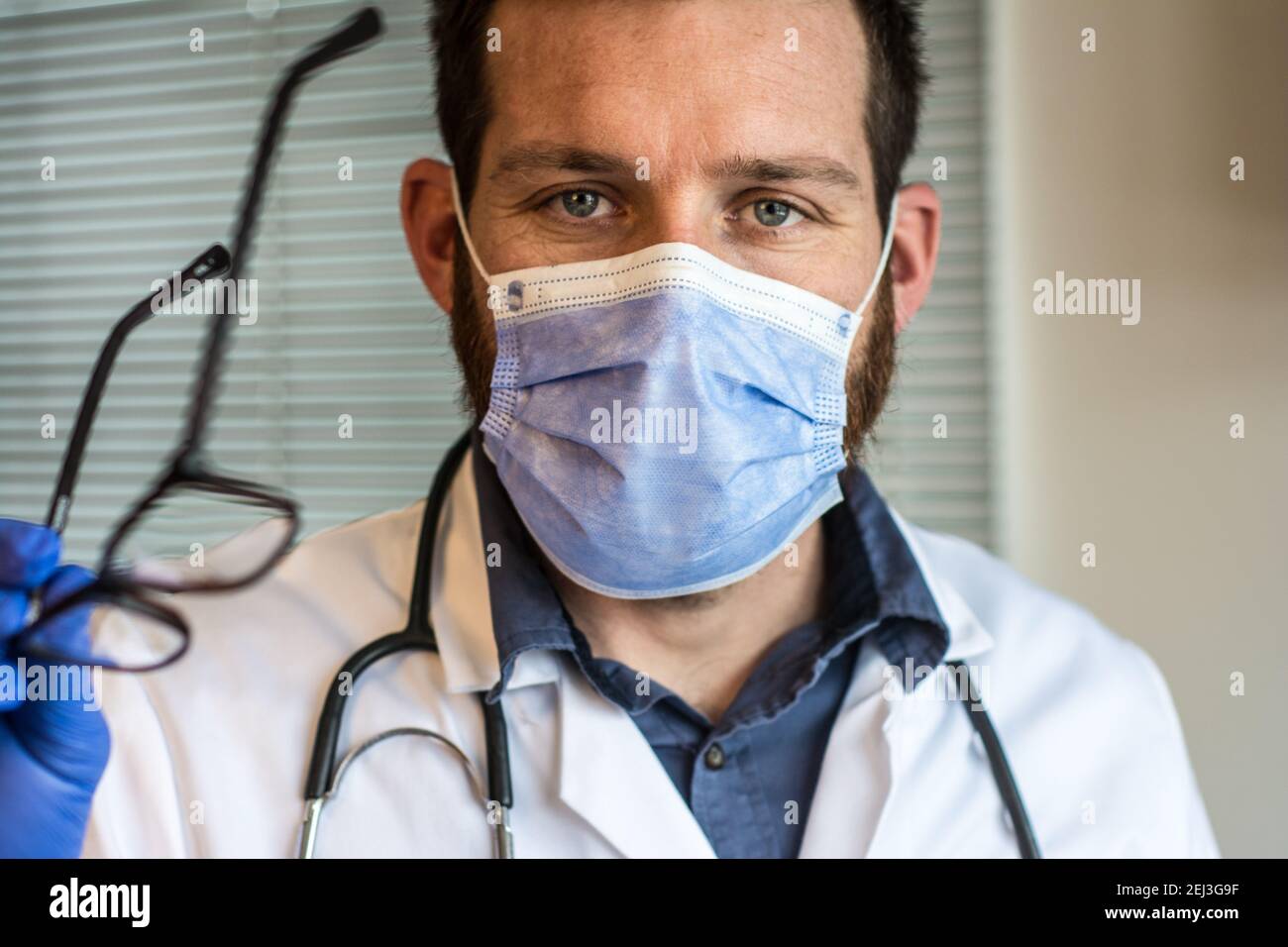 Portrait von schönen männlichen Arzt erklärt mit medizinischen Maske Stockfoto