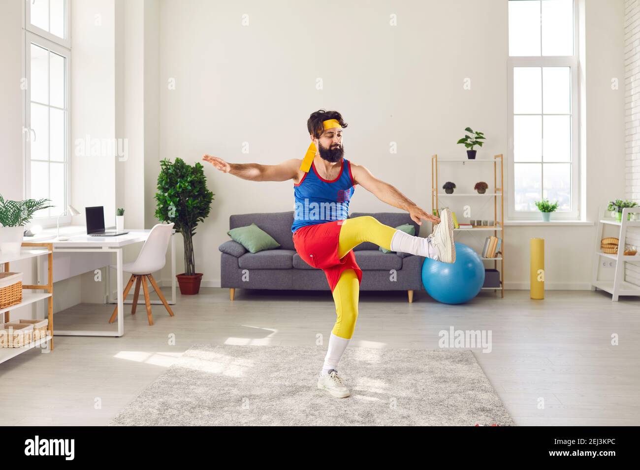 Ungeschickt junger Mann tun Vorderbein heben Zehe Hahn Gymnastik Übung in seinem Wohnzimmer Stockfoto