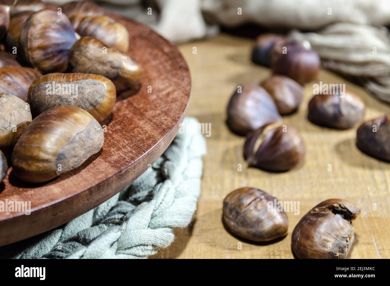 Nahaufnahme von rohen und gerösteten Kastanien auf einem Holztisch. Stockfoto