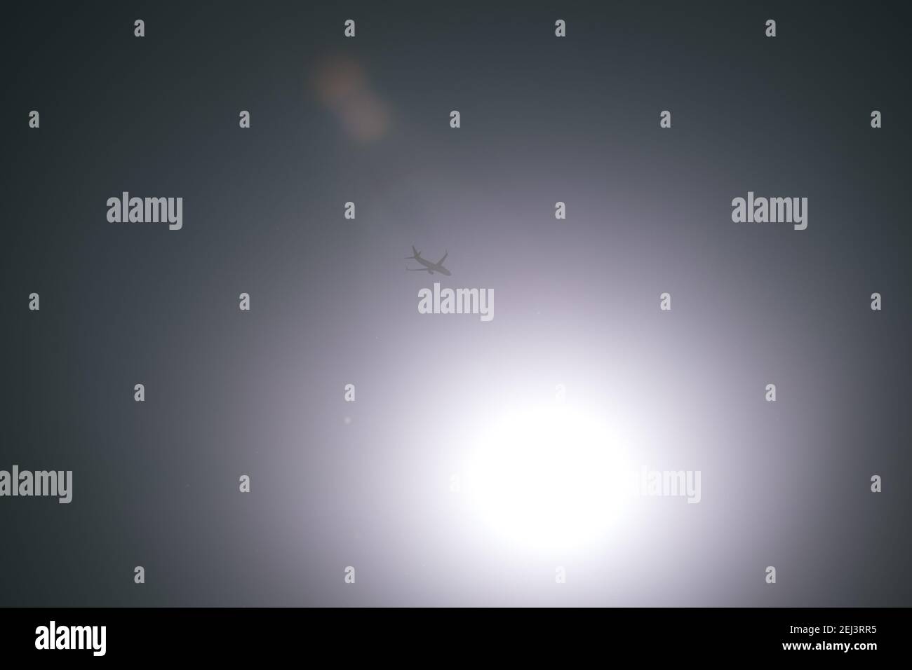 Flugzeug am Himmel mit Sonne am Himmel mit Sonnenreflexion. Reisekonzept Stockfoto