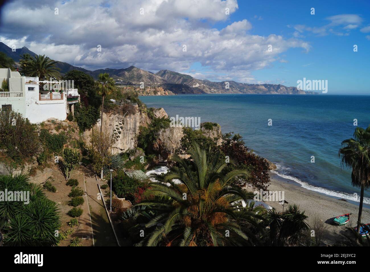 Szenische Aufnahme der Küste von Nerja mit Palmen, Bergen, blauem Himmel und Seeseite Stockfoto